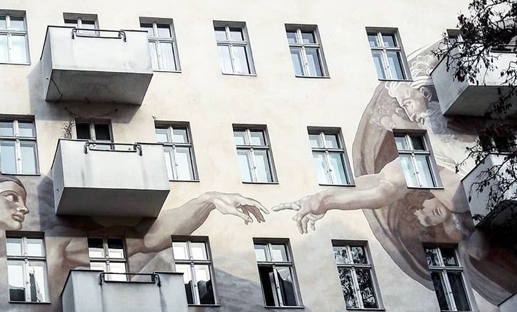 Street art in Berlin: God bringing life to the first man